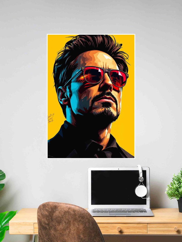 Tony Stark pop art poster with yellow background and red sunglasses, displayed on a wall above a laptop desk setup.